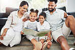 Mixed race family reading a book together on the floor at home. Hispanic mother and father teaching their little son and daughter how to read. Brother and sister learning to read with their parents