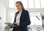 Mature focused caucasian businesswoman working on a digital tablet in an office. One female boss using social media on a digital tablet at work