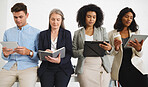 Group of serious diverse businesspeople standing and using digital tablets and writing in notebooks together in an office. Content business professionals working and planning at work