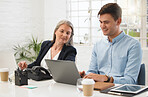 Two caucasian businesspeople working on a laptop together In an office at work. Mature businesswoman looking at a colleagues computer screen. Young businessman typing on a laptop while sitting with a coworker