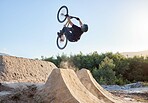 Mountain bike, nature and cyclist man outdoor for sports, travel and adventure with energy, fitness and freedom while cycling, jump and training. Male athlete in air with bicycle for exercise workout