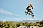 Mountain bike, high jump and athlete doing a trick in nature for a competition or training. Bicycle, fitness and cyclist doing a crazy stunt in the air with adrenaline for a fun sports championship.