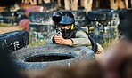 Paintball, person aim gun at target and military tactics, shooting range and war game for sports outdoor. Soldier with weapon on battlefield, action and camouflage, helmet for safety and adventure