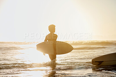 Buy stock photo Back, surf and sunset with a sports man in the ocean during summer for hobby, leisure or recreation. Surfing, sea and nature with a male athlete or surfer walking into the water for health or fitness