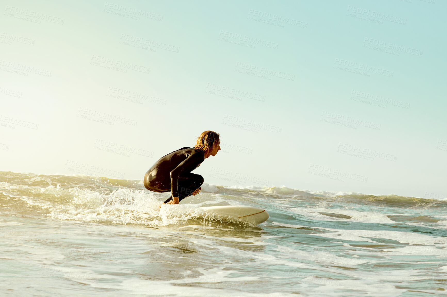 Buy stock photo Sea, surf and blue sky mockup with a man on his surfboard, training or enjoying water sports. Ocean, fitness and surfing with a male athlete in a wetsuit for health, wellness or freedom in summer
