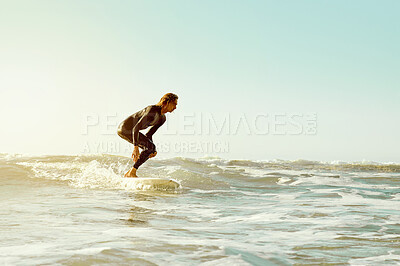 Buy stock photo Sea, surfing and blue sky mockup with a man on his surfboard, training or enjoying water sports. Ocean, fitness and surf with a male athlete in a wetsuit for health, wellness or freedom in summer