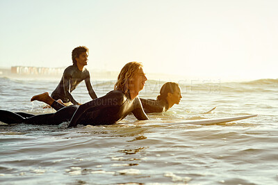 Buy stock photo Sunset, adventure and friends surfing at the beach while on a summer vacation, travel or weekend trip. Watersports and group of people practicing to surf in the ocean at twilight on tropical holiday.