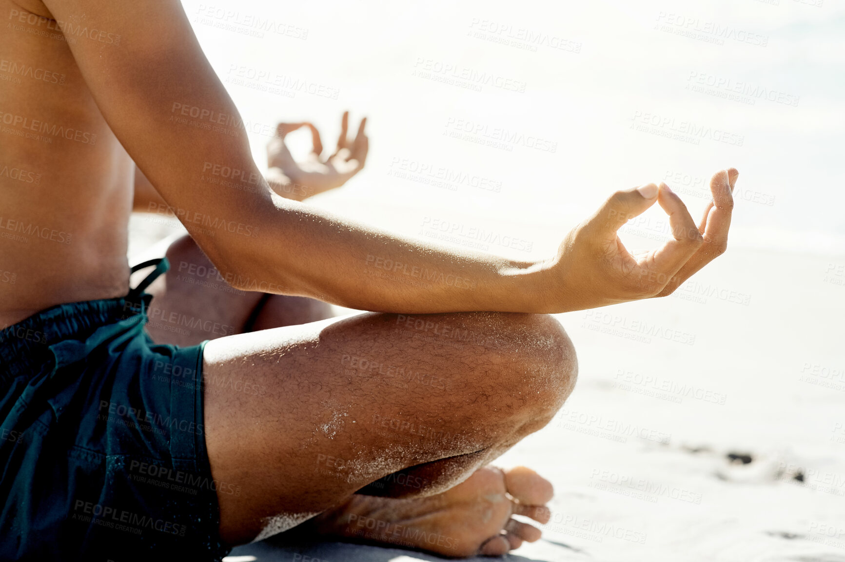 Buy stock photo Hands, zen and meditation with a man on the beach, sitting legs crossed for wellness on the sand by the ocean. Yoga, balance and inner peace with a male meditating near the sea for mental health