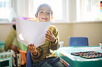 Portrait, kids and art with a girl in class, holding paper while looking creative or learning at school. Children, education and a cute female child sitting in a classroom for artistic development