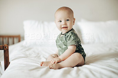 Buy stock photo Cute, young and portrait of a baby on a bed sitting and playing in his modern nursery at home. Happy, smile and sweet infant boy child being playful while in his bedroom at a house or apartment.