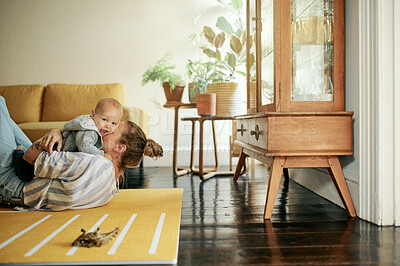 Buy stock photo Family, play and mother kiss baby in home for bonding, quality time and relax together on floor. Living room, love and happy mama with kid playing for child development, care and loving on weekend
