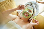 Portrait, skincare and woman with face mask and cucumber on couch in lounge. Beauty, happiness or person with facial treatment for dermatology, healthy or flawless skin, natural cosmetics or top view