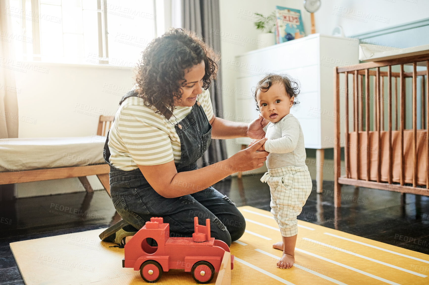 Buy stock photo Mother, family and baby learning to walk with help and toys in bedroom for development. Woman and child together for support, walking and growth or playing for fun while holding hands for care