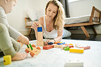 Wooden blocks, baby toys and mother playing with child in family home bedroom for fun. Woman or mom with toddler child together for quality time, learning and building mobility or growth development