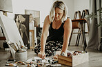 Woman, painting and creative art in studio, home or house, squeezing tube of color paint for canvas. Artist person and relax painter with talent for design in workshop