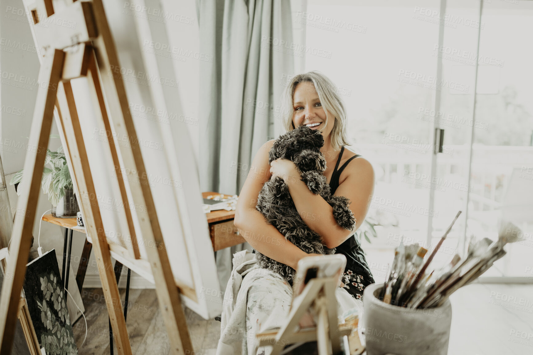 Buy stock photo Artist portrait, dog and happy woman hug animal for love, support and care in creative apartment, home studio or art workshop. Smile, creativity or relax designer, painter or person embrace furry pet