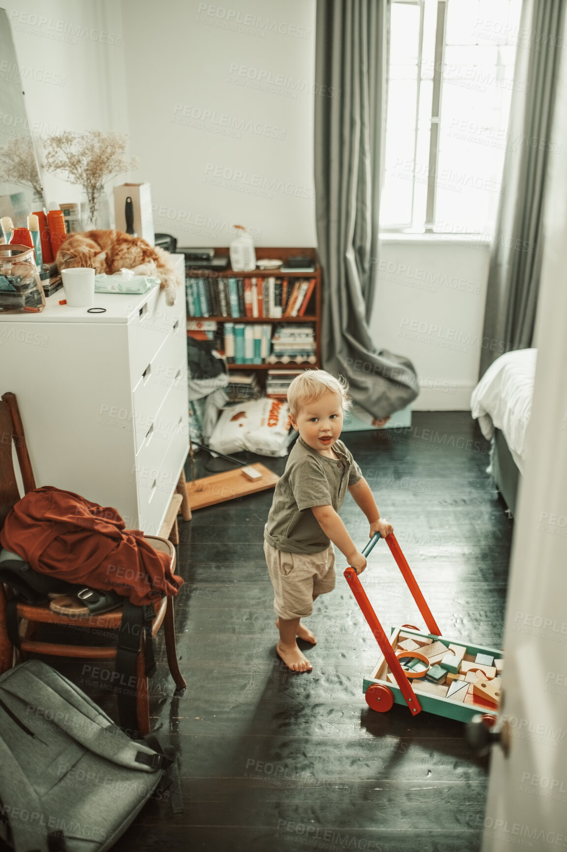 Buy stock photo Cute, toys and boy toddler playing in his nursery for child development and fun at home. Playful, sweet and portrait of a little infant kid walking with a wood barrow in his bedroom in the house.