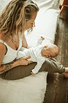 Bonding, love and mother holding her baby while relaxing on a sofa in the living room of her home. Happy, smile and young mom sitting and looking at her newborn or infant child in their family house 