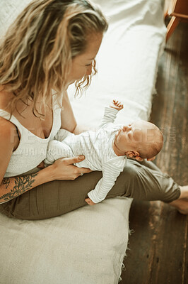 Buy stock photo Bonding, love and mother holding her baby while relaxing on a sofa in the living room of her home. Happy, smile and young mom sitting and looking at her newborn or infant child in their family house 