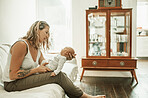 Love, sweet and mom with her newborn baby while relaxing on a sofa in the living room of her home. Happy, smile and young mother sitting, bonding and looking at her infant child in their family house