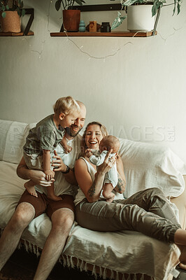 Buy stock photo Bonding, family and parents with baby and toddler on a sofa with smile, care and relax in their home together. Newborn, love and mother and father with children in a living room enjoying parenthood