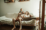 Parents, children and a family laughing on the sofa in the living room of their home together for bonding. Mother, father and kids in the house with a baby and playful boy child sitting in the lounge