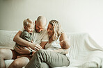 Family, bonding and parents with baby and toddler on a sofa with smile, care and relax in their home together. Newborn, love and mother and father with children in a living room enjoying parenthood