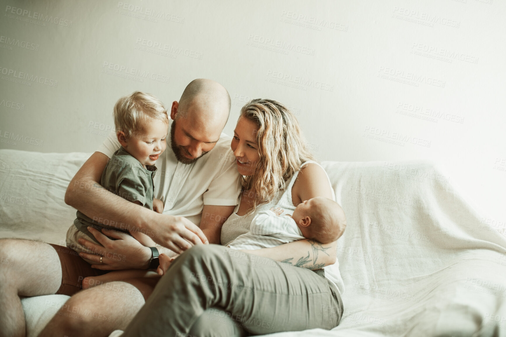 Buy stock photo Family, bonding and parents with baby and toddler on a sofa with smile, care and relax in their home together. Newborn, love and mother and father with children in a living room enjoying parenthood