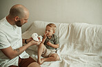 Playing, father and child on a home sofa with a toy for bonding and weekend fun. Show, family and a playful young dad with toys and a boy kid on the couch for education, game or activity together