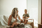 Bonding, portrait and toddler with mother and baby relaxing on a sofa in the living room of their home. Bonding, love and young mom talking to her infant and newborn child in their family house.