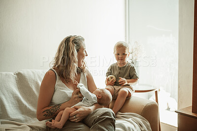 Buy stock photo Bonding, portrait and toddler with mother and baby relaxing on a sofa in the living room of their home. Bonding, love and young mom talking to her infant and newborn child in their family house.