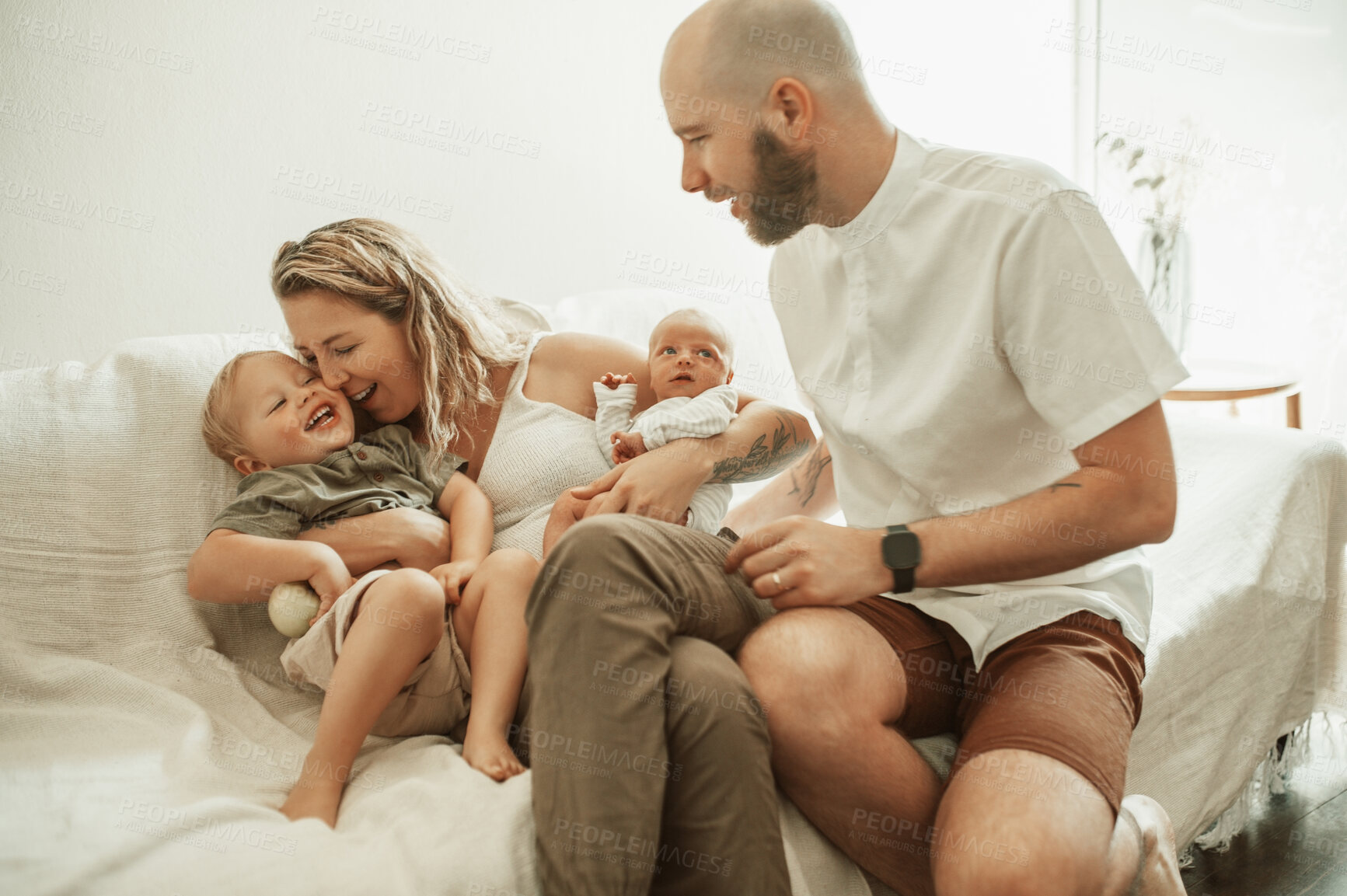 Buy stock photo Love, playful and couple bonding with their kids on a sofa in the living room of their house for family time. Happy, embracing and parents playing and relaxing with newborn baby and toddler at home.