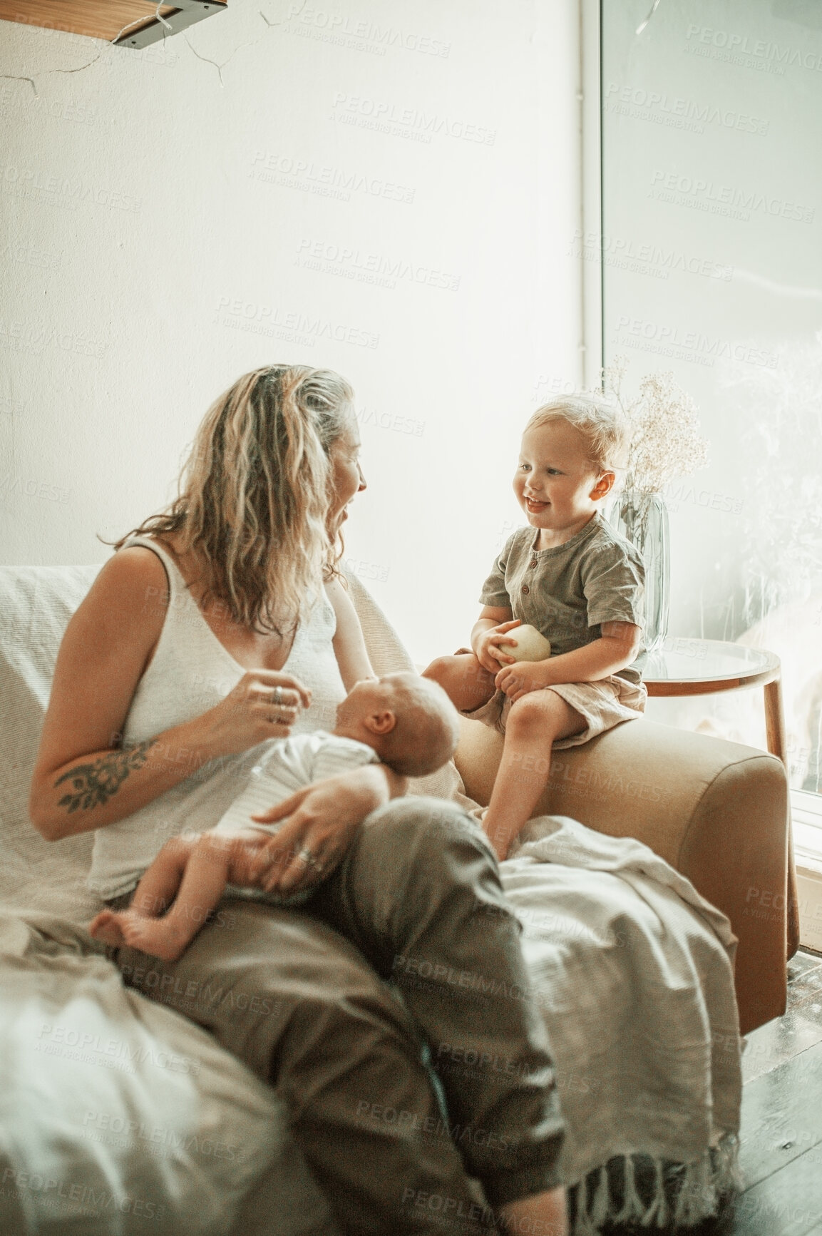 Buy stock photo Love, happy and mother with her toddler and baby relaxing on a sofa in the living room of their home. Happiness, sweet and young mom talking to her infant and newborn child in their family house.