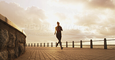 Buy stock photo Woman, sunset and running silhouette by beach, promenade cardio and outdoor for weight loss. Female person, sports training and active athlete in nature, dusk challenge and practice routine by sea