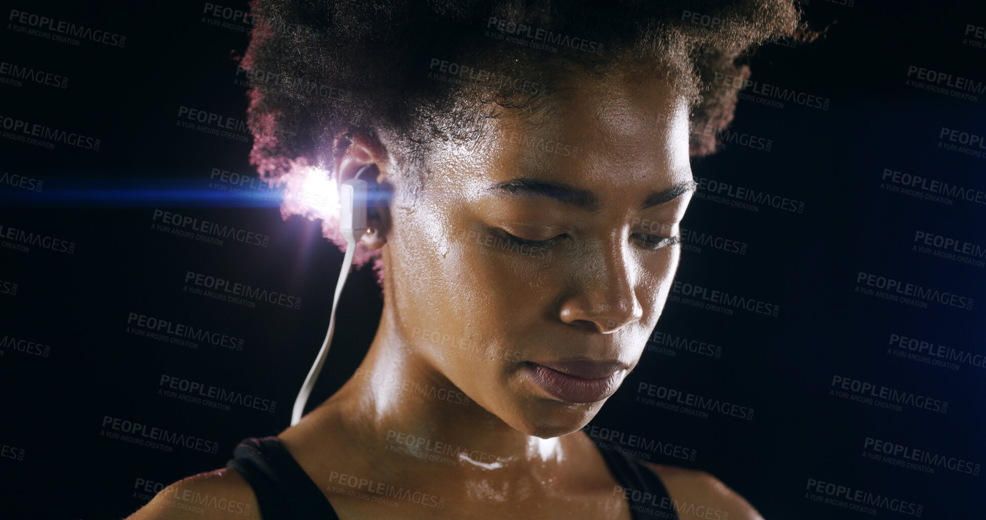 Buy stock photo Earphones, fitness and face of black woman in studio for intense training, exercise and workout. Sports, lens flare and person sweating for wellness, health and listening to music on dark background