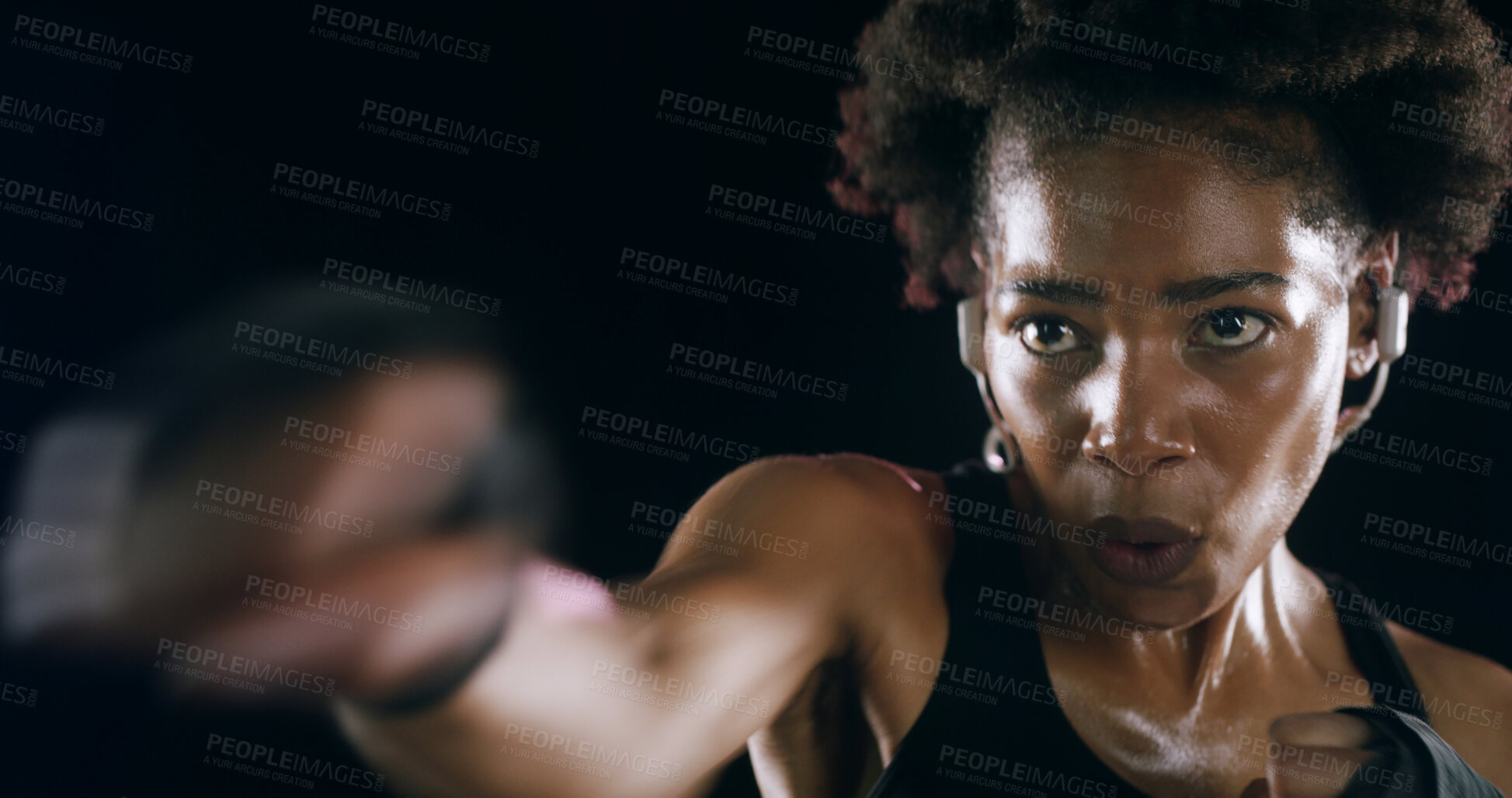 Buy stock photo African woman, punch and earphones for training, fitness and music for martial arts by black background. Girl, person and boxing with audio streaming, exercise or workout in studio for fight contest