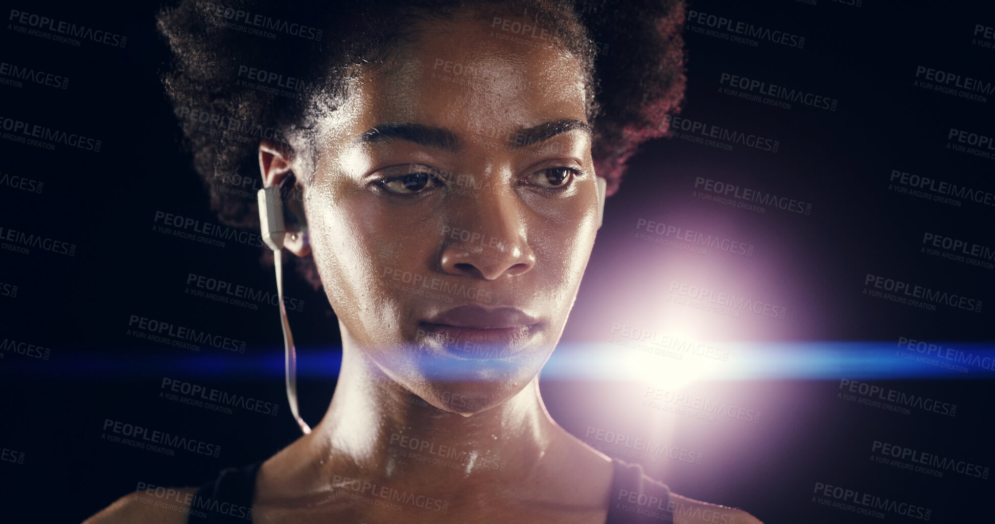 Buy stock photo Earphones, fitness and black woman at night for training, exercise and intense workout. Sports, lens flare and face of person sweating for wellness, health and listening to music on dark background