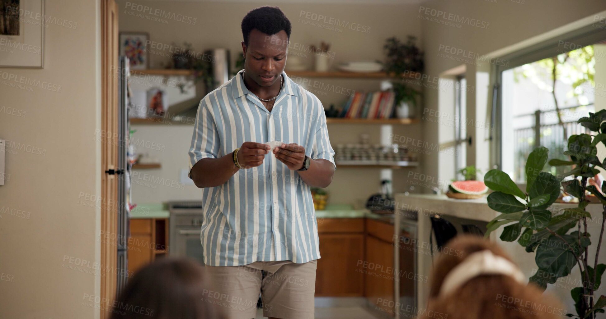 Buy stock photo Man, game and card in home with friends for challenge, solution and answer together. Person acting, playing pantomime and party for reading, social gathering or thinking in living room at house