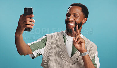 Buy stock photo Selfie, peace sign or happy black man in studio with confidence, video call or fashion clothes. Smile, hand gesture or influencer on blue background for social media post, photo or vlogging update 