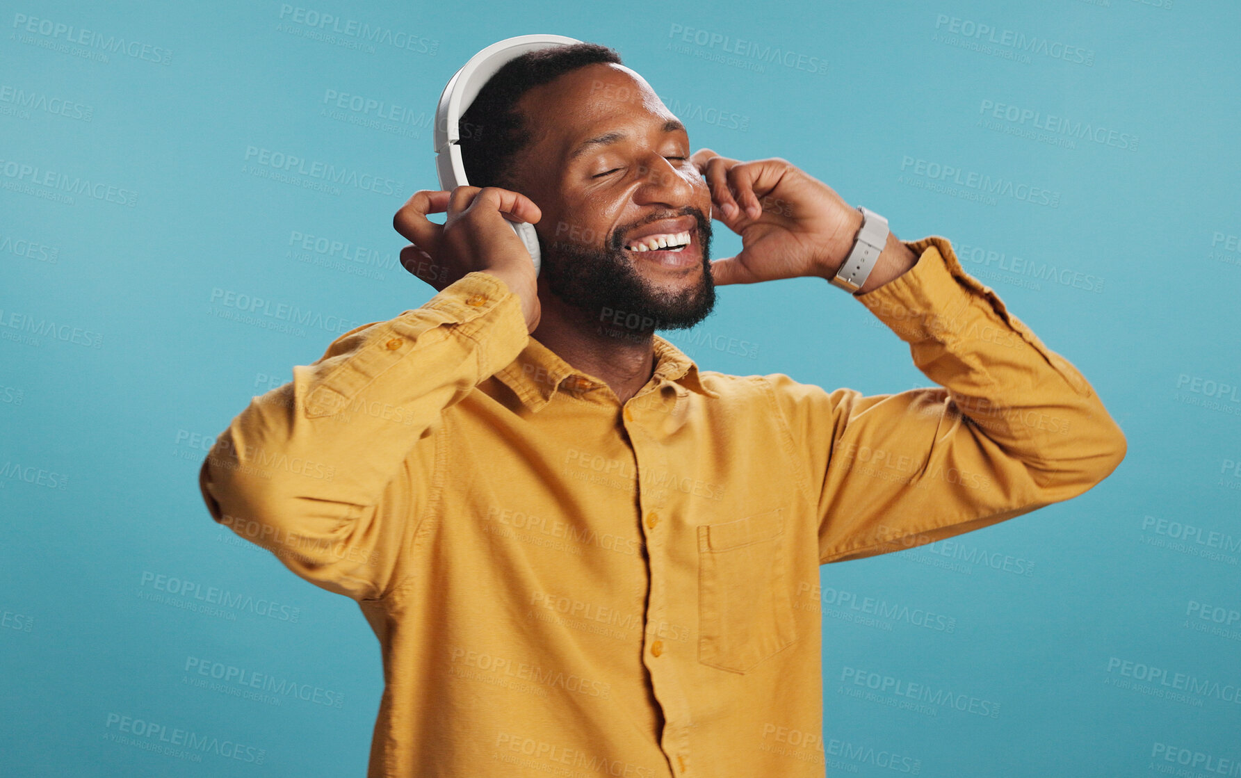 Buy stock photo Headphones, smile and black man in studio with music, playlist or album for review on blog. Happy, audio tech and African male influencer listening to song online for streaming app by blue background