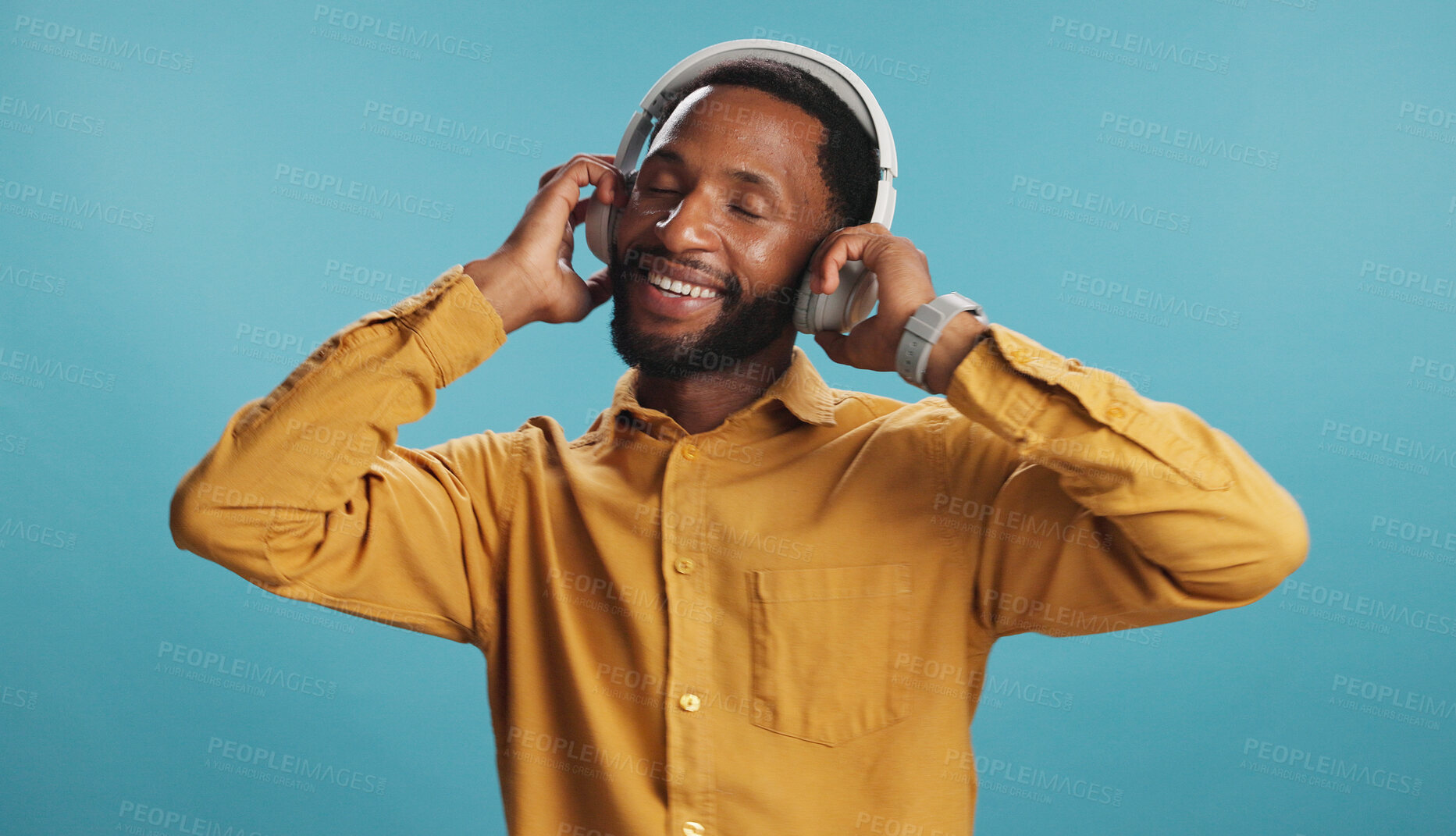 Buy stock photo Headphones, excited and black man in studio with music, playlist or album for review on blog. Smile, audio tech and African influencer listening to song online for streaming app by blue background