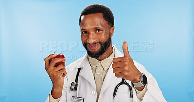 Buy stock photo Thumbs up, doctor and black man with apple in portrait for fibre, healthcare advice or healthy food choice. Studio, blue background or happy African nutritionist with fruit for approval and vitamin c
