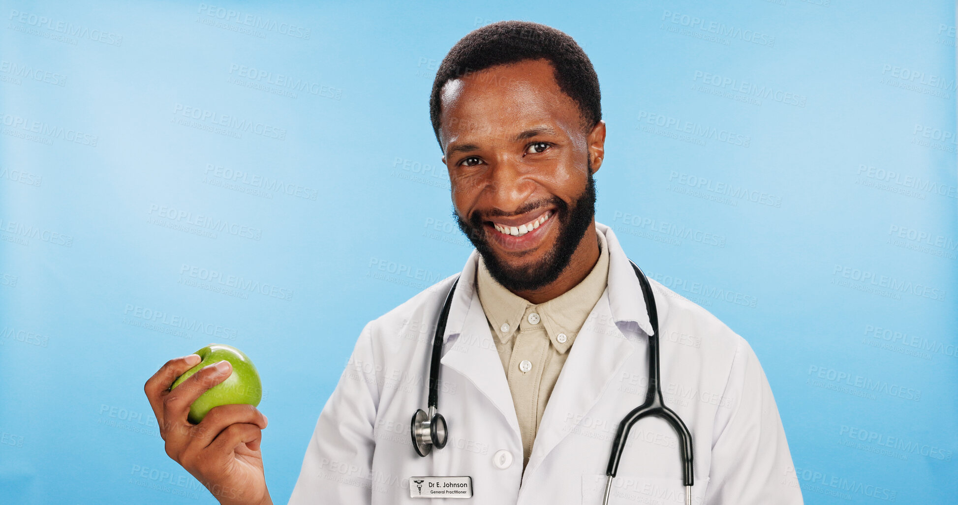 Buy stock photo Happy, doctor and black man with apple in portrait for diet, healthcare advice or healthy food choice. Studio, blue background or African nutritionist with smile for fresh fruit, fiber or vitamin c