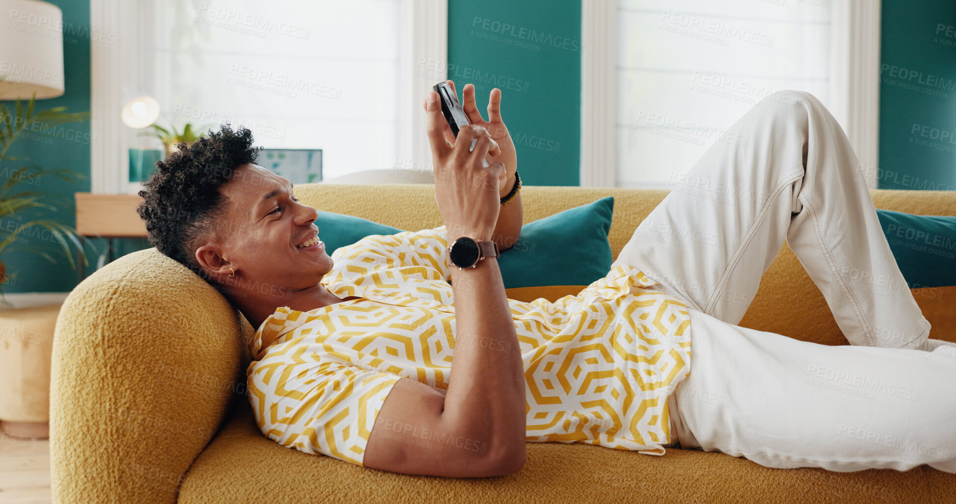Buy stock photo Mobile, relax and happy man in home, reading blog and content creator post on social media profile. Phone, sofa and person on chat app for communication, check notification and playing game online