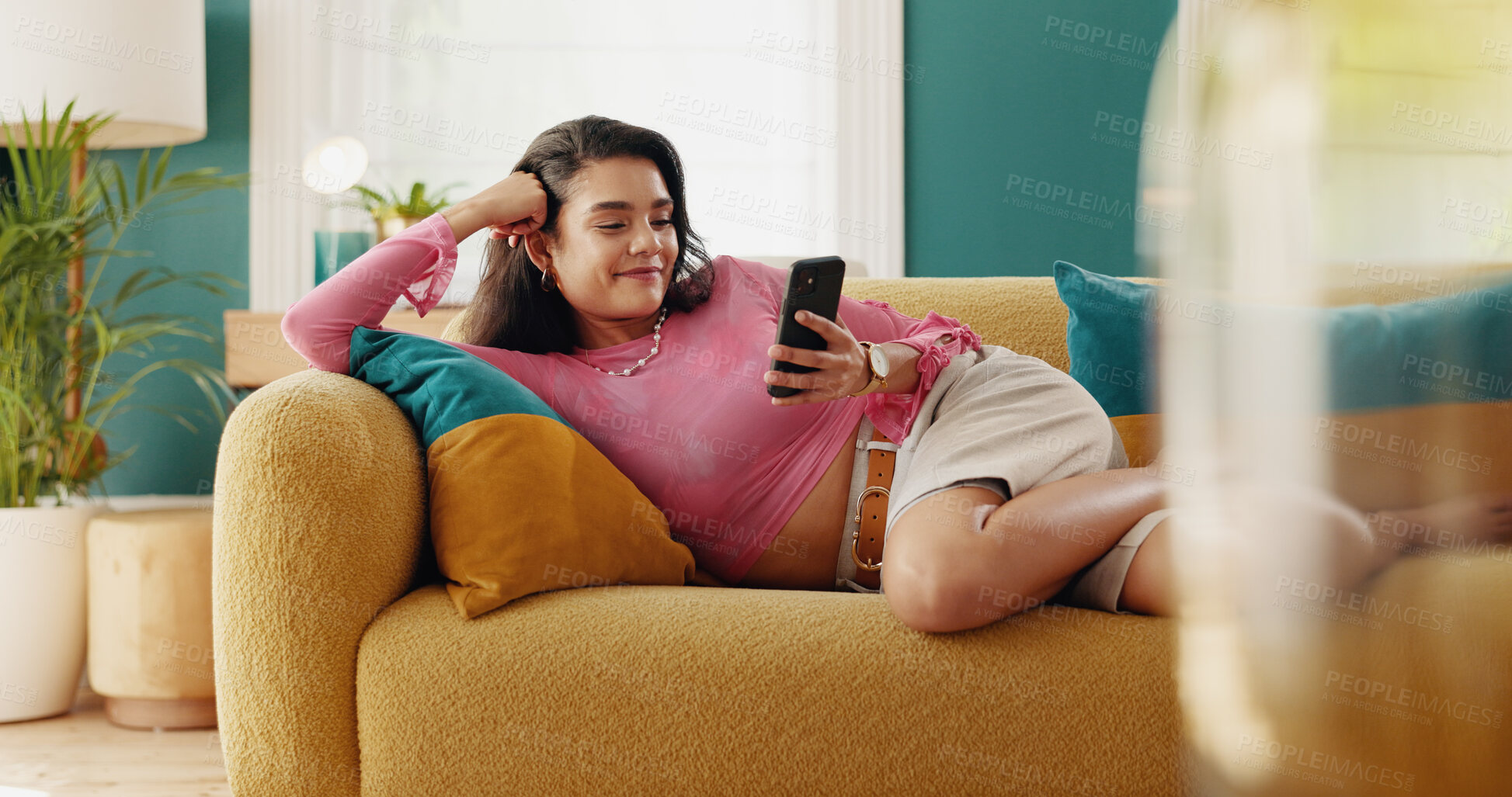 Buy stock photo Phone, relax and happy woman on sofa, reading ebook and watch video on social media. Mobile, home and girl on chat app for communication, check notification and streaming service on internet to chill