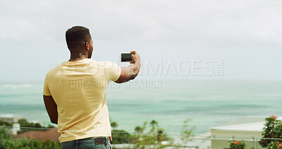 Buy stock photo Travel, photography and man at ocean with phone, memory and tropical vacation at hotel from back. Holiday blog, live stream and influencer at beach with smartphone for online review for island resort
