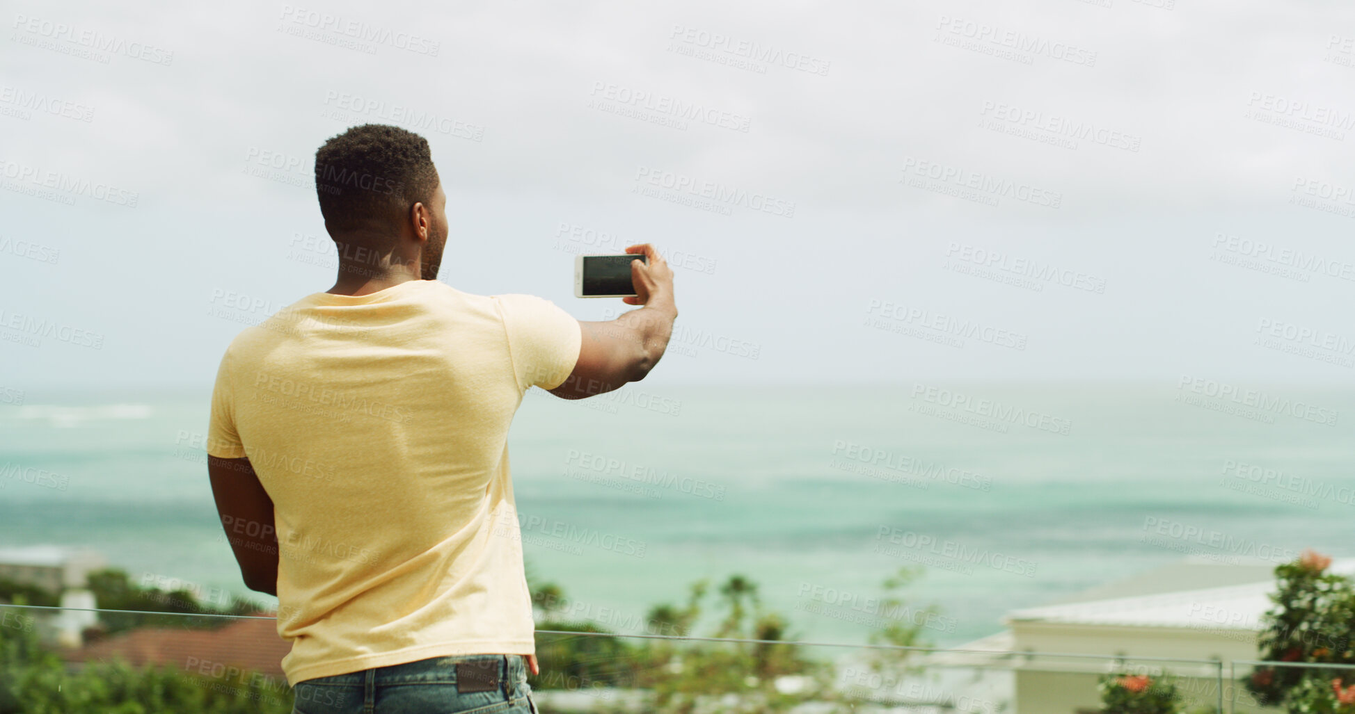 Buy stock photo Travel, photography and man at ocean with phone, memory and tropical vacation at hotel from back. Holiday blog, live stream and influencer at beach with smartphone for online review for island resort