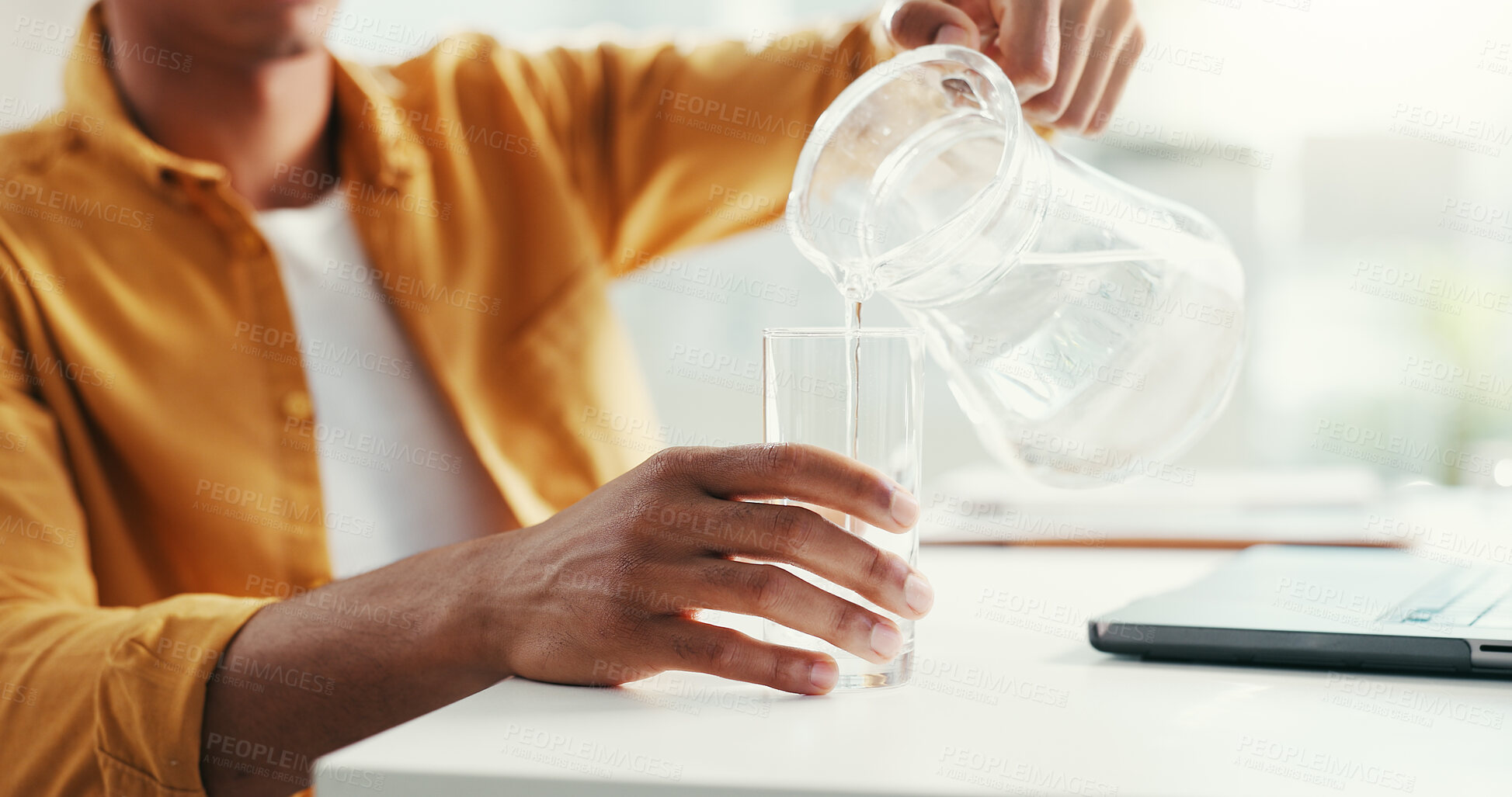 Buy stock photo Hands, thirsty and water with business person pouring drink at desk in office for break or hydration. Health, laptop and refreshment in glass jug with design employee in creative workplace closeup