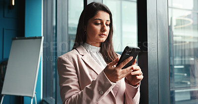 Buy stock photo Contact, phone and update with business woman at window in boardroom of office for communication. App, networking and text message with serious employee in corporate workplace to check schedule