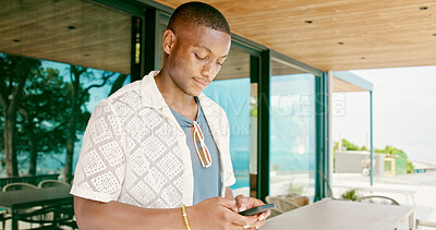 Buy stock photo Black man, typing and outdoor with phone for social media, travel planning and contact at hotel. Person, mobile or scroll at resort for status update, accommodation review or writing blog on platform
